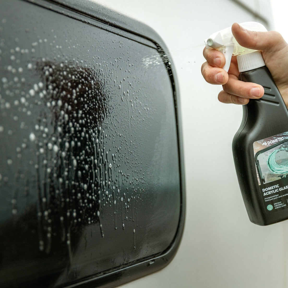 Acrylglas-Reiniger wird auf ein Camperfenster gesprüht